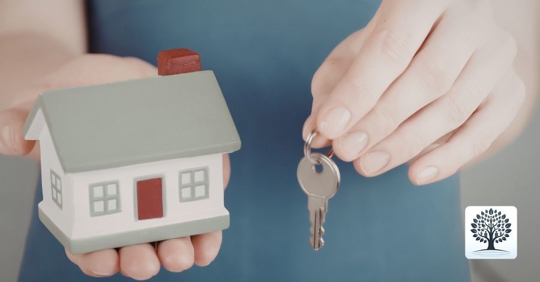 person holding a house figurine and a key